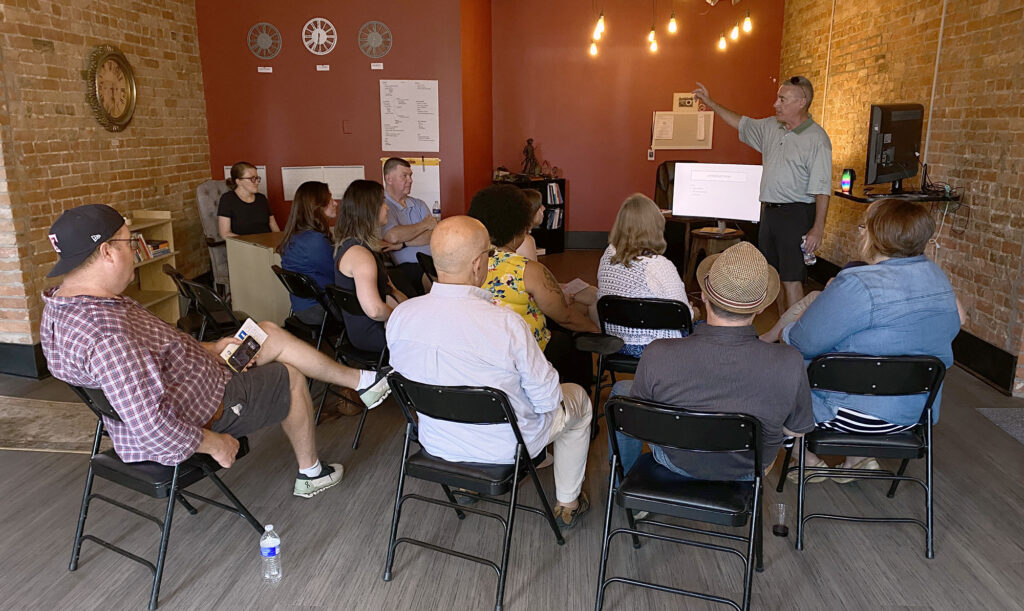 Publisher Tom Pounds stands in front of about 12 people in the office and tells them of the history of the Toledo Free Press.